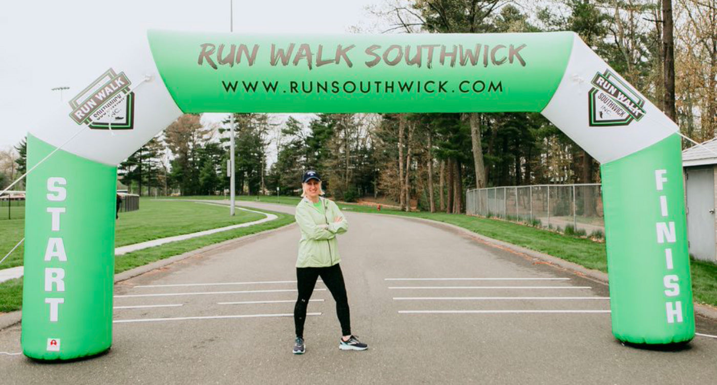woman posing under inflatable arch at marathon finish line