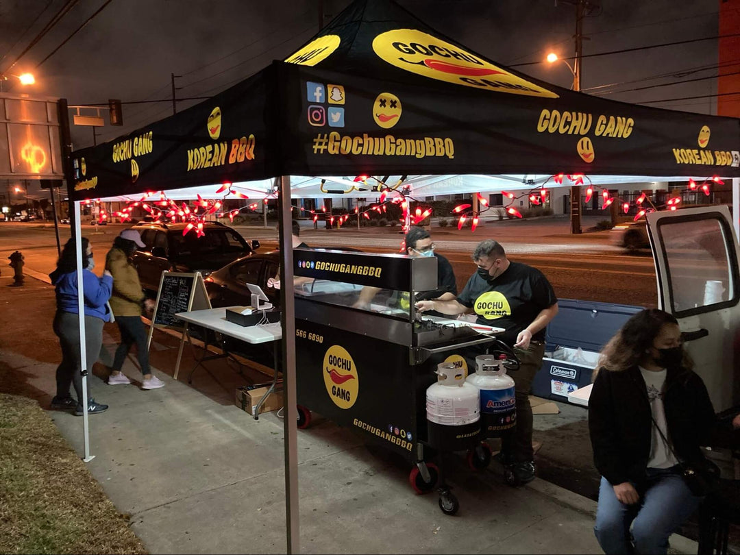 10x10 concession tent for 'GOCHU GANG Korean BBQ' with red accent lights at night