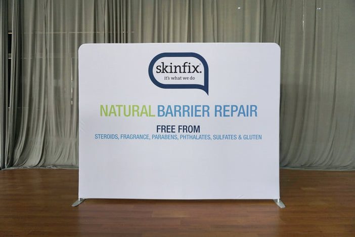 tension fabric pop up backdrop customized for skinfix with white background on a hardwood floor