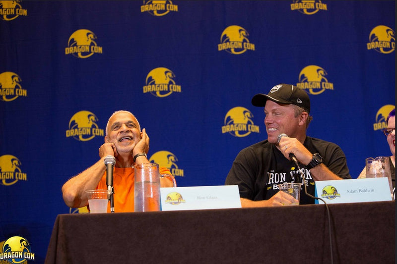 Panelists laughing at Dragon Con with a pop-up backdrop display behind them