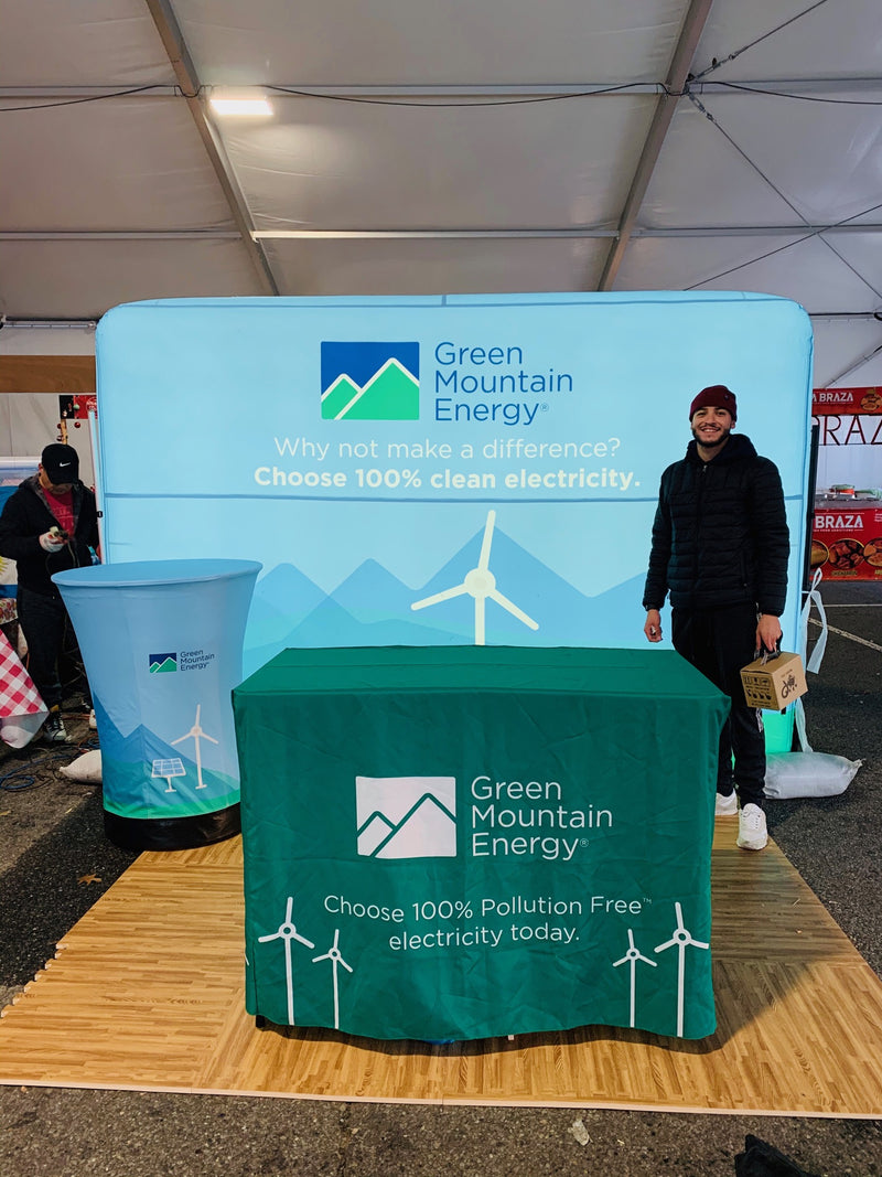Green Mountain Energy promotional booth with a person standing beside a custom podium and branded tablecloth