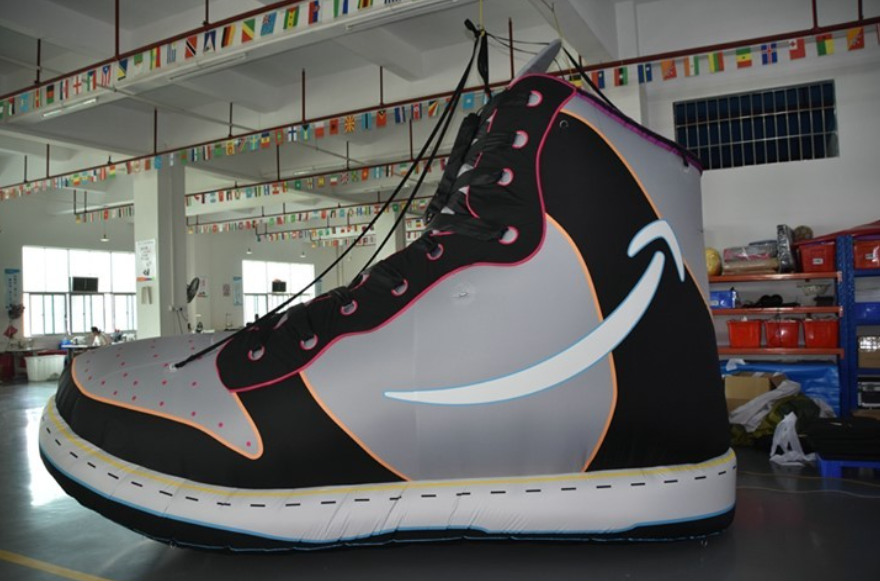 Giant custom-made inflatable sports shoe displayed in a production facility.