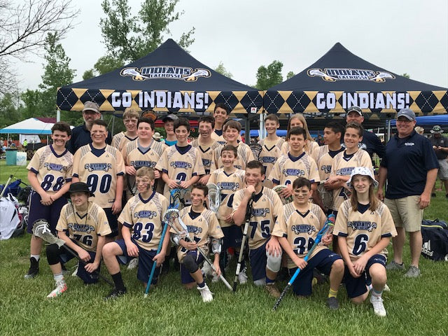 Lacrosse team posing in front of school sports tents with GO INDIANS! slogan