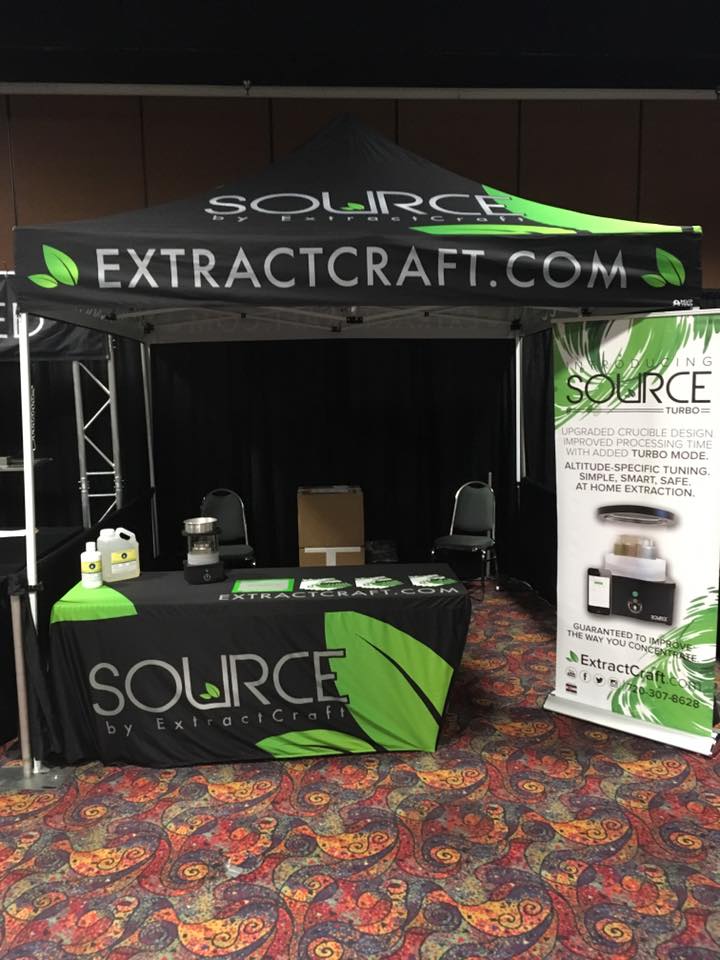 Retractable banner stand with ExtractCraft branding and product information at a trade show booth