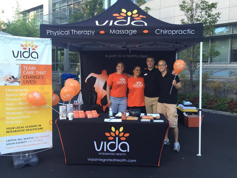 Custom stretch table covers with Vida Integrated Health logo displayed at a trade show booth