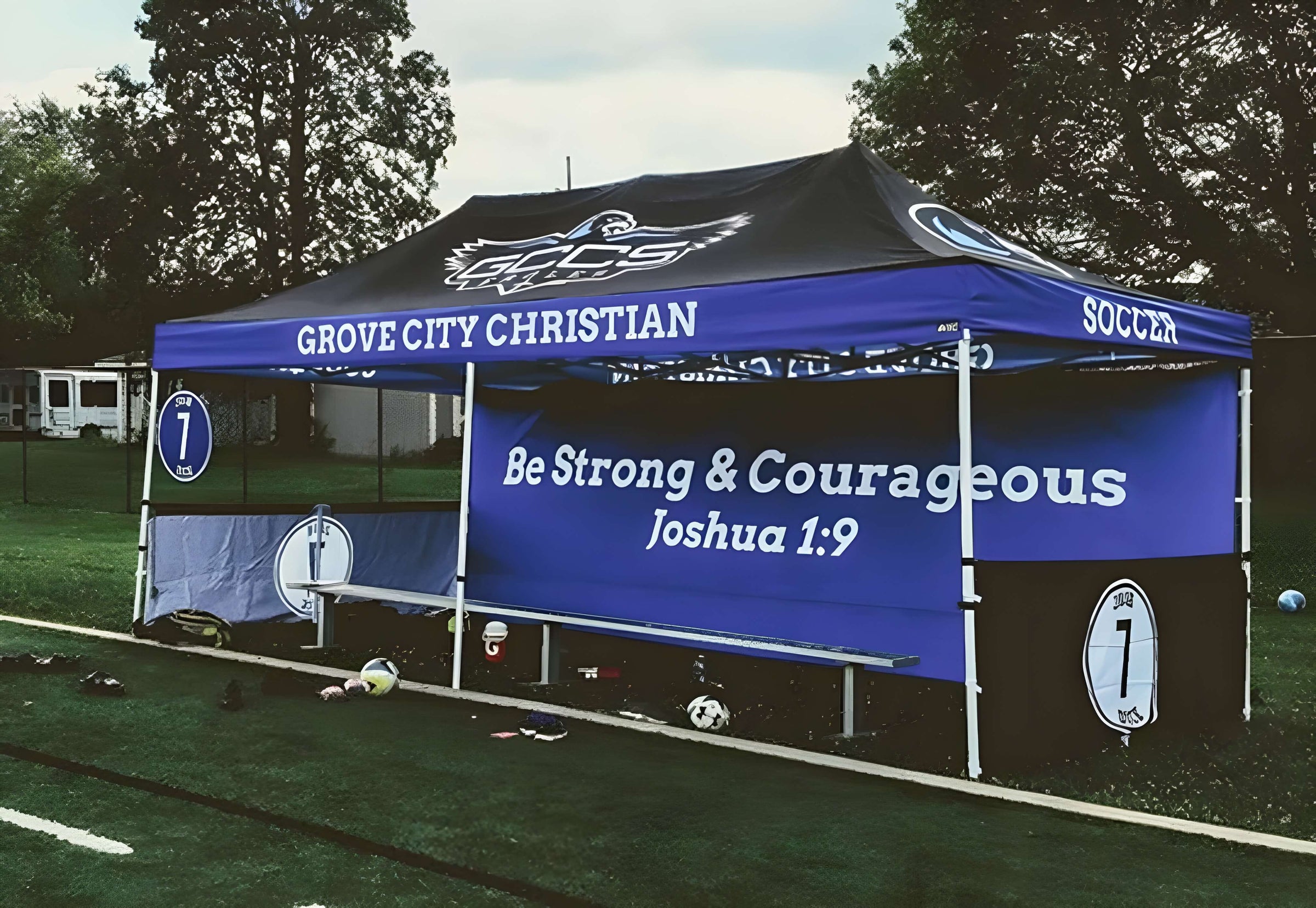 Blue and black tent with 'Grove City Christian' branding and motivational quote on a sports field.
