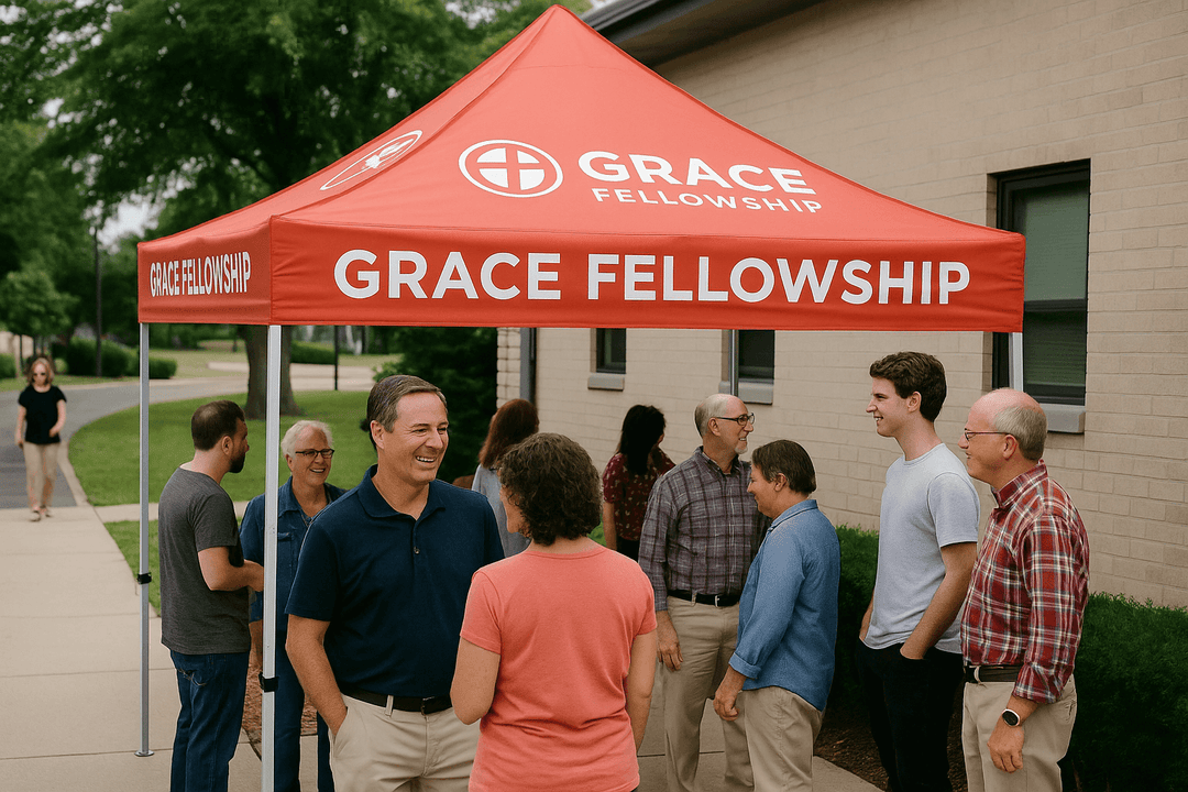 Group of people standing under a red 'Grace Fellowship' canopy.