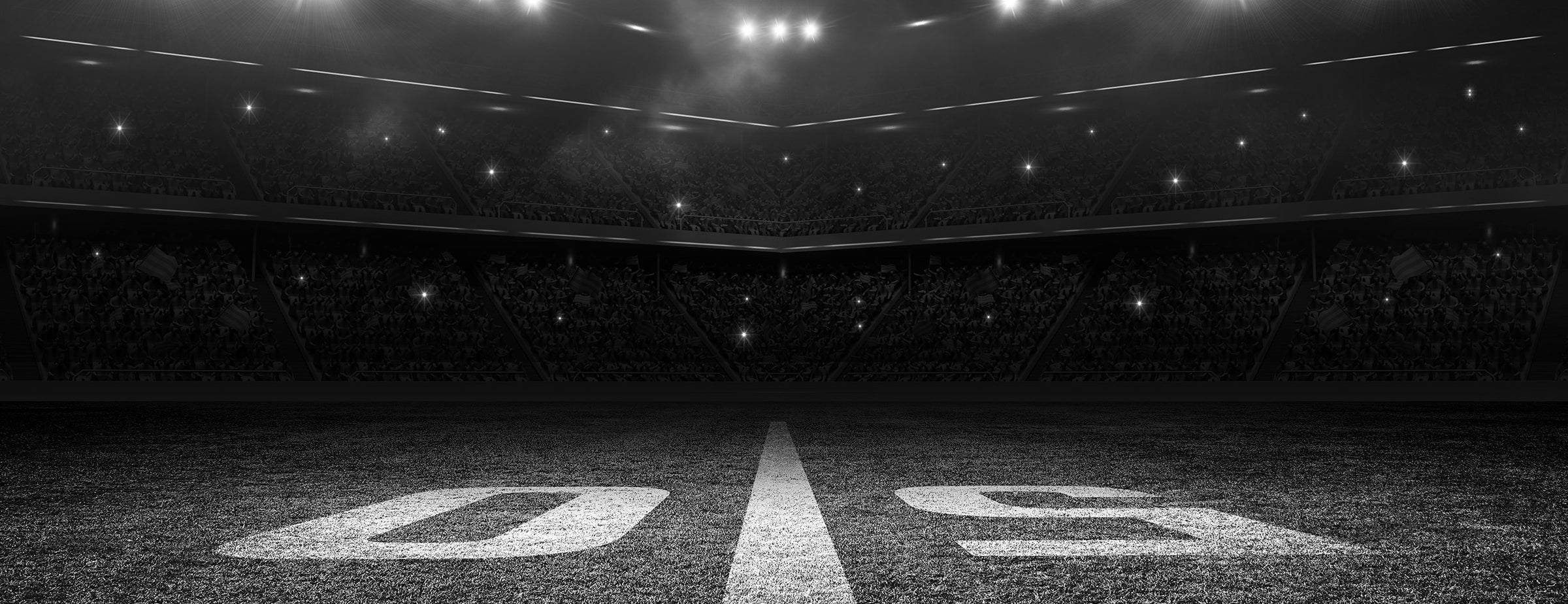 Monochrome image of a packed stadium with illuminated field lines for a sporting event.
