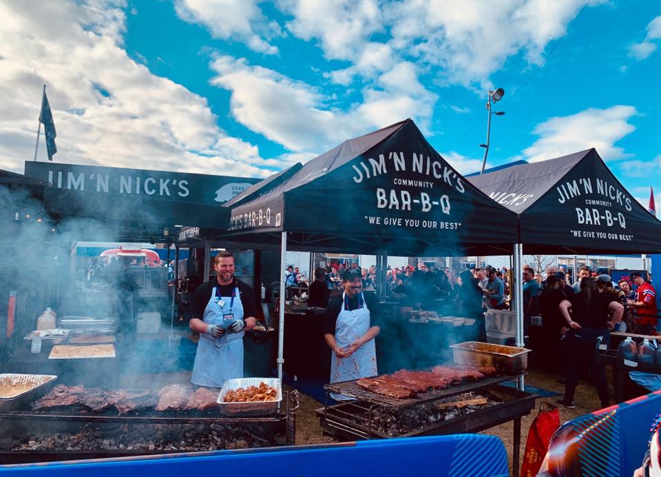 Jim 'N Nick's BBQ food service tents with smoke and bustling crowd at festival