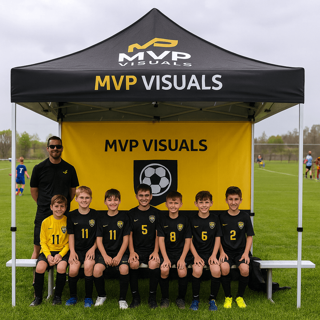 Group of children in sports uniforms posing under a MVP Visuals tent on a sports field.