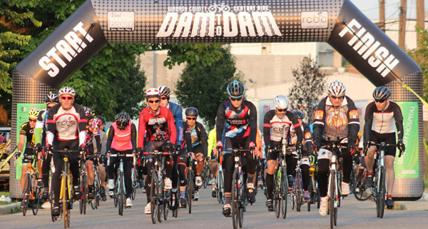 Cyclists at the starting line passing through a custom inflatable arch at a bicycle racing event