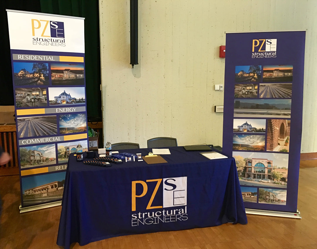10x10 trade show booth with custom table throw and retractable banners by PZSE Structural Engineers