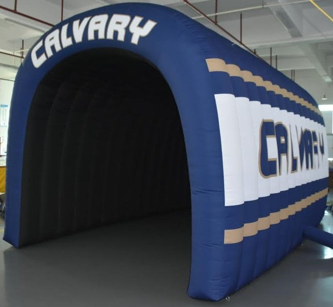 Angled back view of Calvary inflatable tunnel in navy, white, and gold for school sports team entry