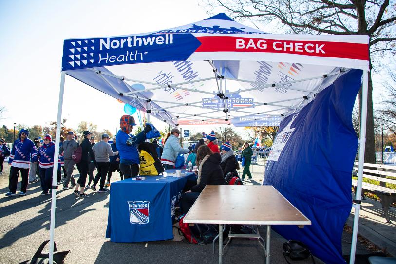A Bag Check tent at the NY Rangers 5K run, bustling with runners and fans on a sunny morning