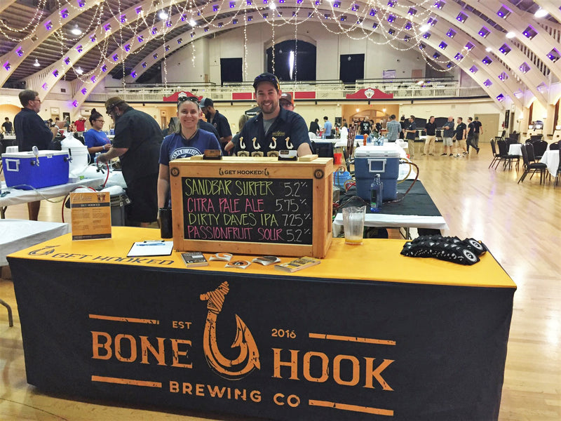 fitted custom table cover for bone hook brewing company with two employees smiling in the back of the table