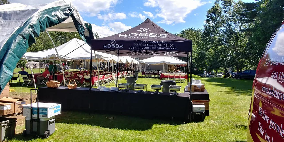 Canopy tent for restaurant catering set up in a park with serving tables ready for an event