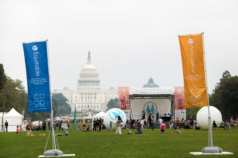 Custom vertical flag displays at a coop festival with Capitol building in the background