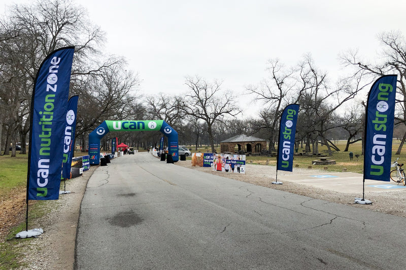 An outdoor racing path with blue feather flags printed for UCAN Chicago brand and an finish line arch