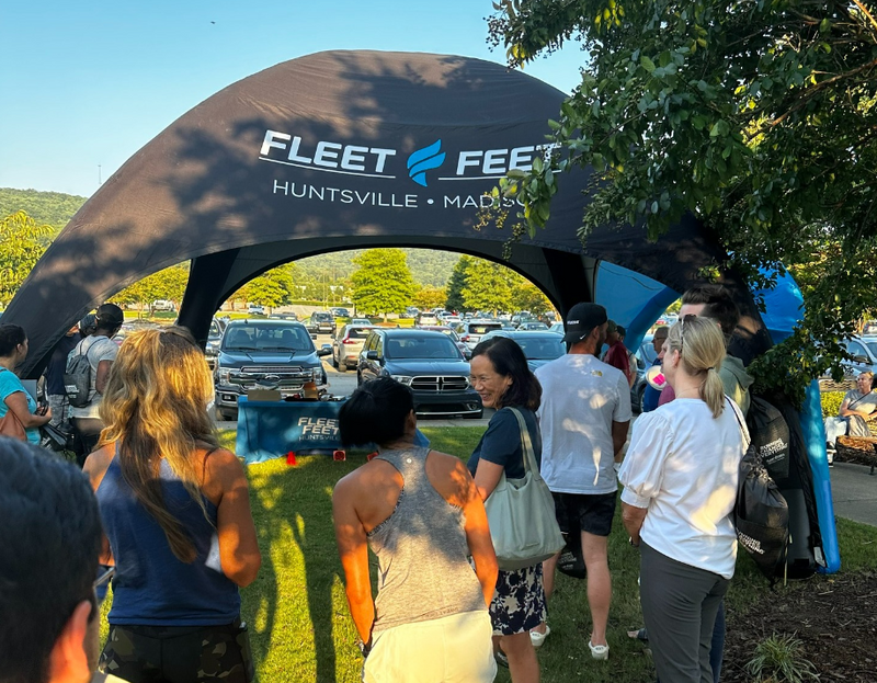 Branded inflatable dome tent by Fleet Feet, bustling with event participants