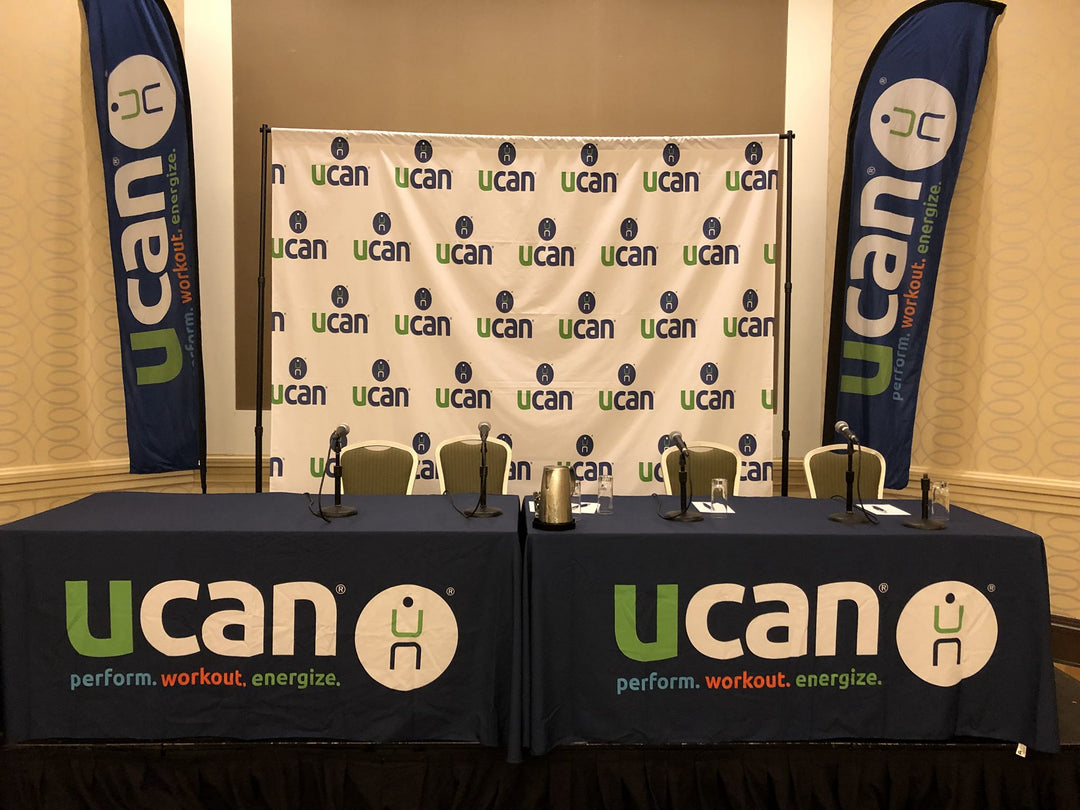 Ucan nonprofit booth displays showcasing custom tablecloth, feather flag and backdrop banner.