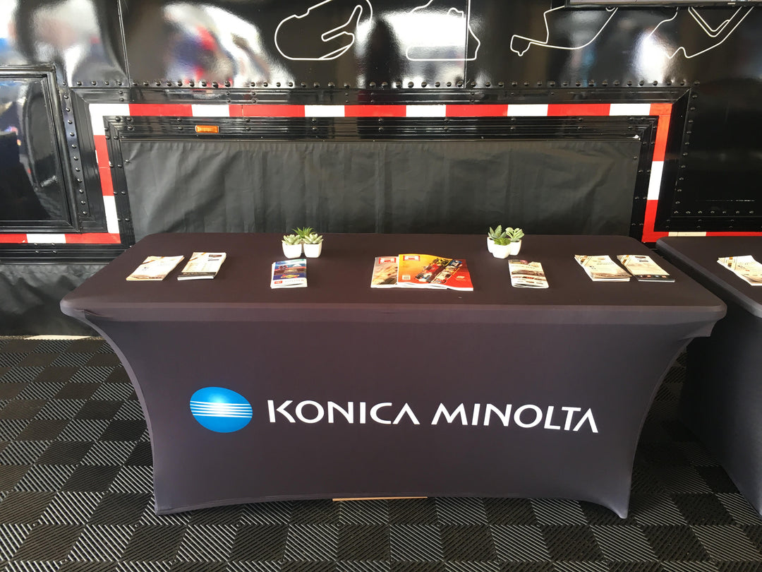 Elegant black stretch table cover with the Konica Minolta logo for a professional trade show display