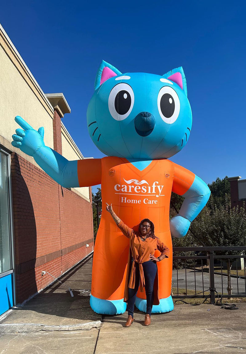 giant inflatable cat mascot of caresify home care brand with a woman posing in front of it