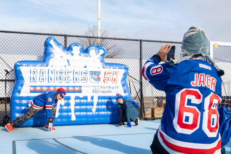 NY Rangers Hockey fans pose in front of a large Rangers 5K inflatable logo at a 5k run