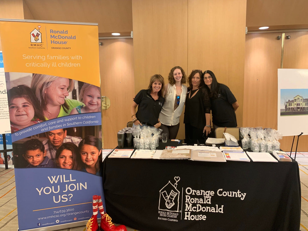 Ronald McDonalds orange county nonprofit chapter members behind branded tablecloth and retractable banner.