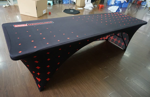 Sleek black stretch trade show table cover with red diamond pattern, designed for easy access and legroom