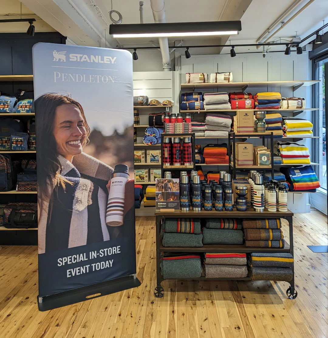 A tension fabric banner stand advertising a special in-store event today at a retail shop with Stanley and Pendleton products