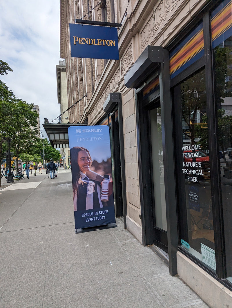 Pendleton store exterior with tension fabric banner advertising a special in-store event, city sidewalk