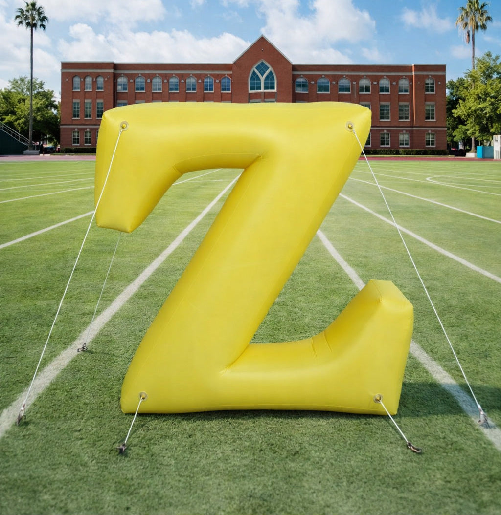 Large yellow inflatable letter 'Z' on a sports field with a building in the background