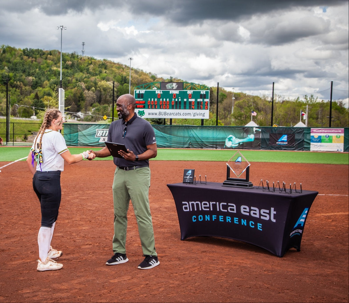 Person receiving an award on a baseball field with 'America East Conference' table cloth branding.