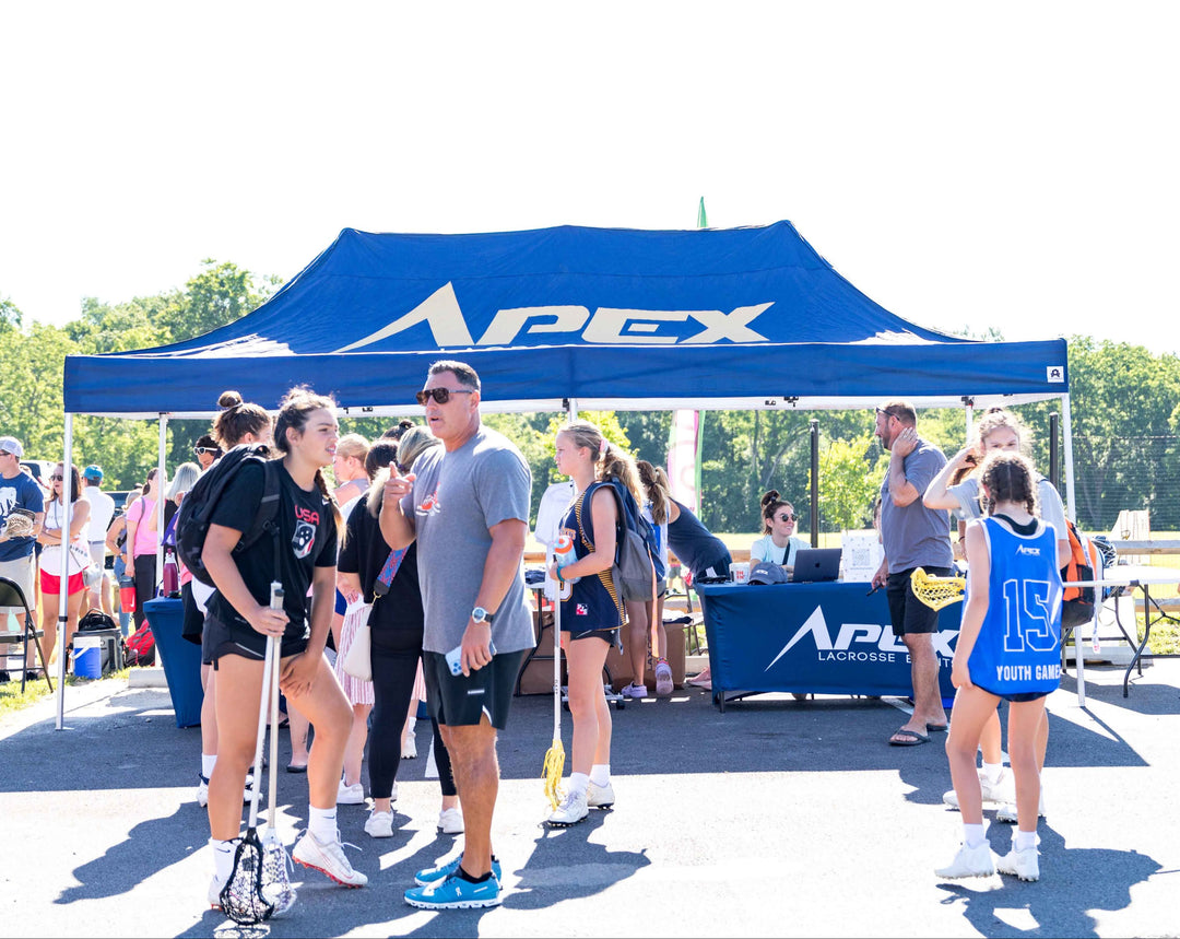 Blue custom 10x20 canopy tent for APEX Lacrosse Events with athletes gathering at tournament