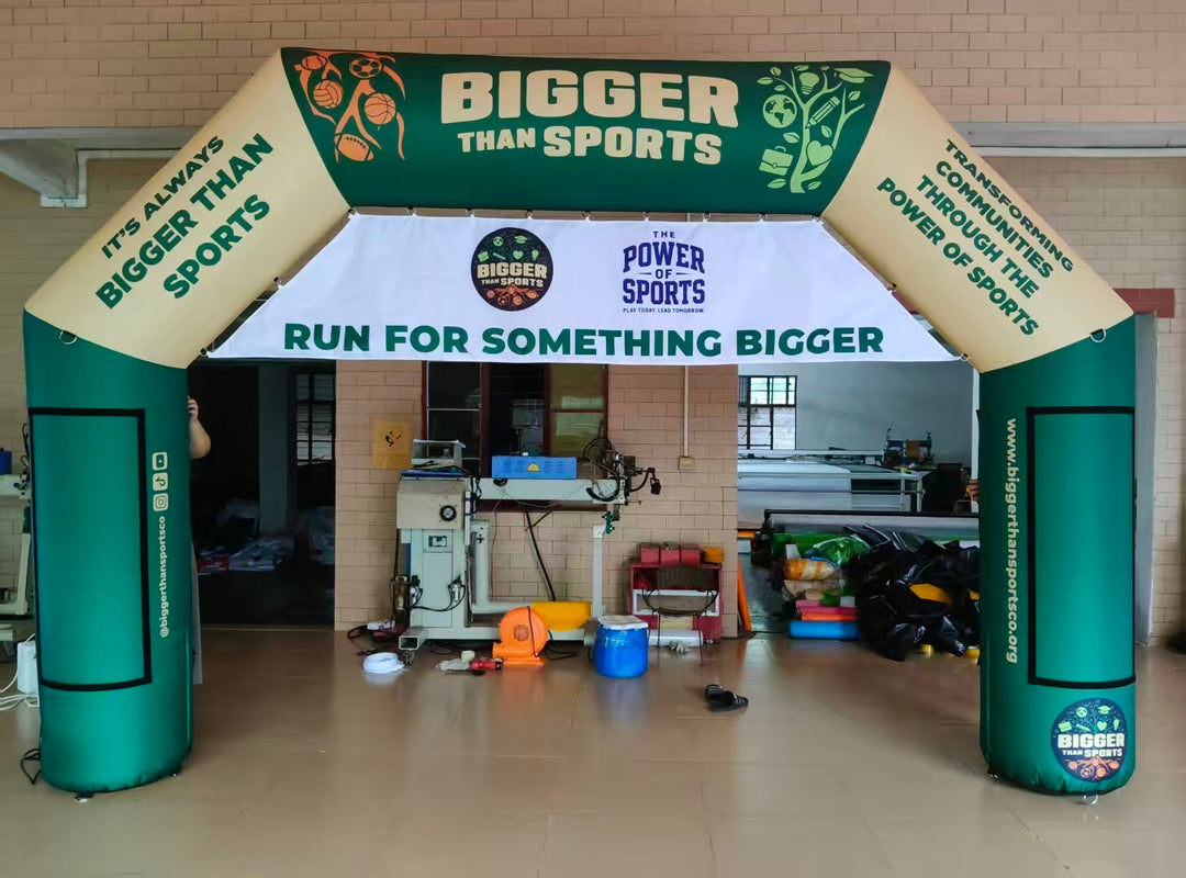 Green and tan inflatable arch with sports icons and 'Bigger Than Sports' branding, featuring a race banner