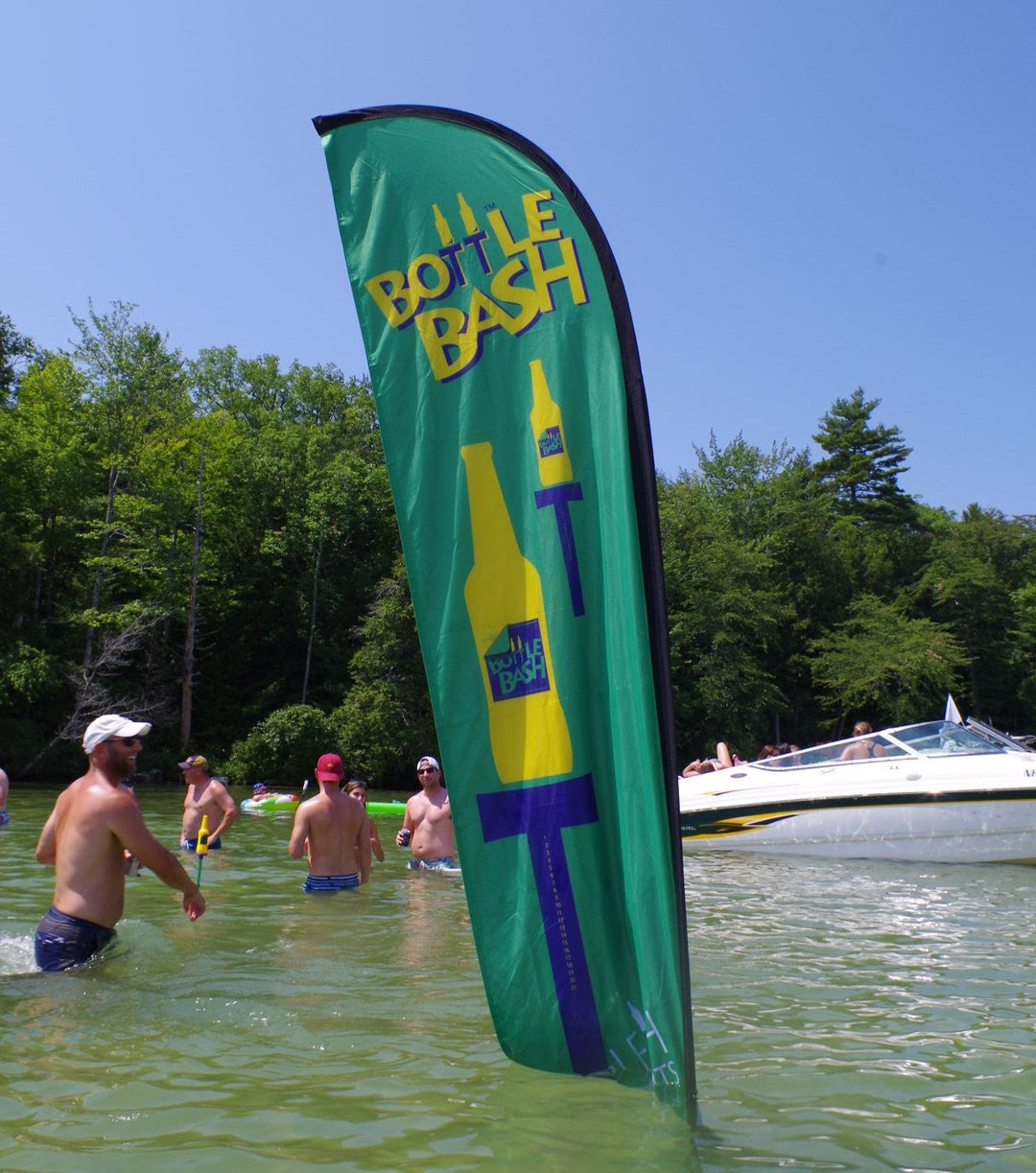 Green Bottle Bash feather flag in lake during summer event with swimmers and a boat nearby.