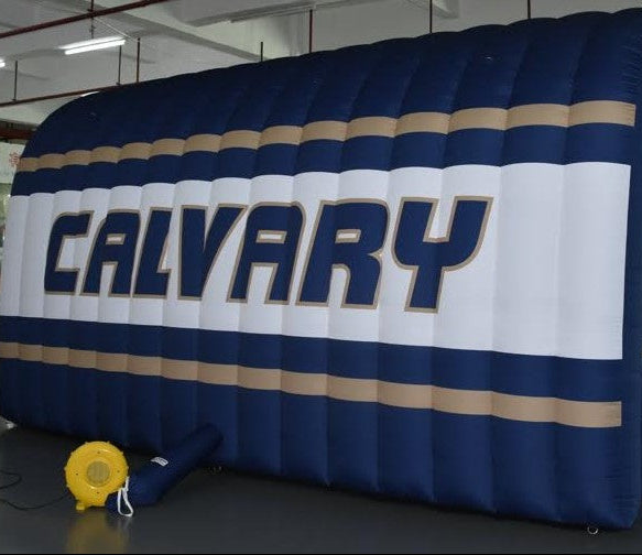 Side view of Calvary inflatable tunnel in navy, white, and gold with large printed lettering for school sports entrances
