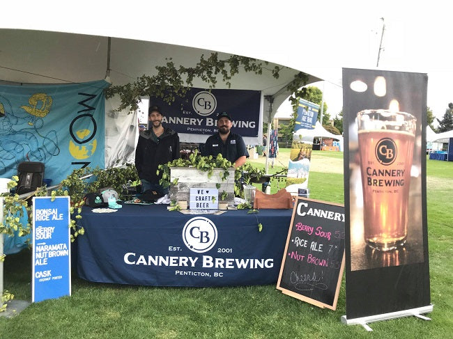 Cannery Brewing booth at an outdoor event with branding and promotional materials.