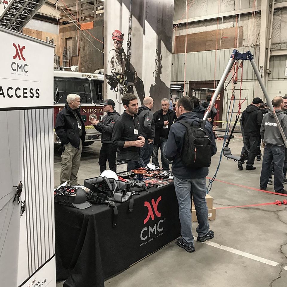 People gathered around a table with CMC branding in an industrial setting