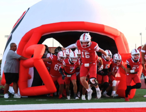 Cotton Pickers football players running out of inflatable helmet tunnel onto the field during game entrance.