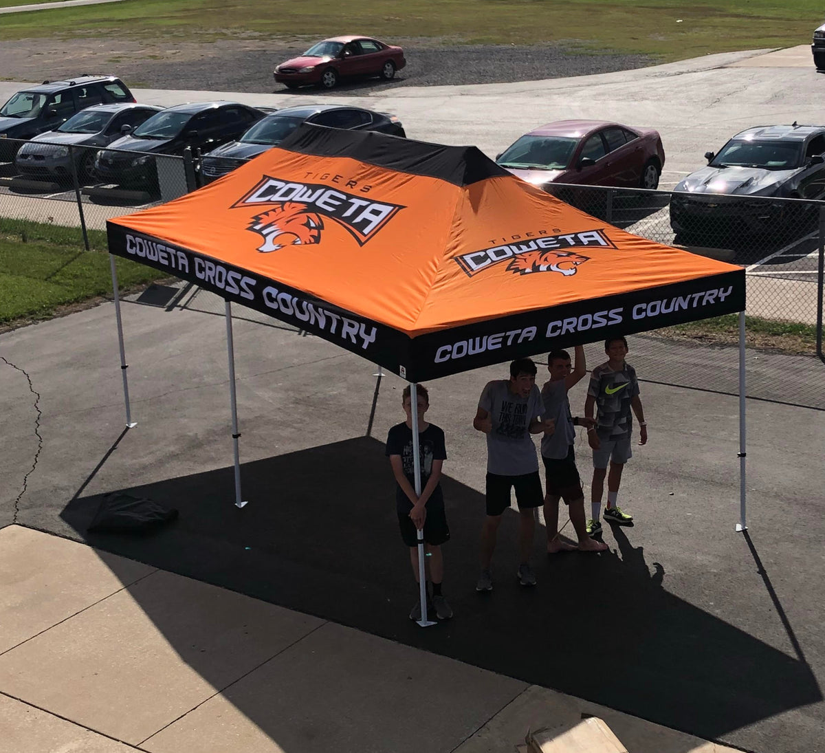 Custom 10x20 canopy tent for Coweta Cross Country with tiger mascot, set up outdoors near school parking lot