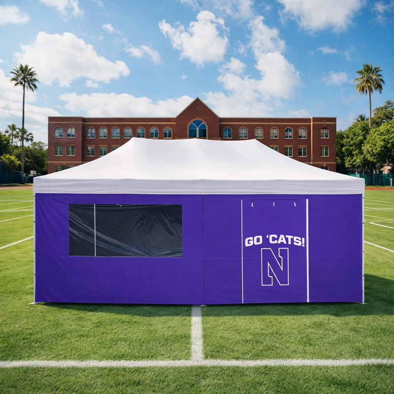 Purple and white tent with 'GO 'CATS!' and 'N' logo on a grassy field with a building in the background.