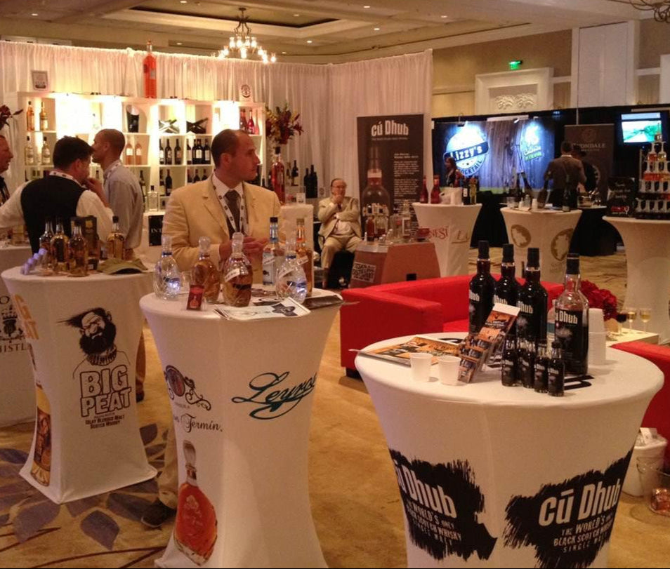 Custom high table spandex covers for multiple spirits brands at International Wine and Spirits event with product displays