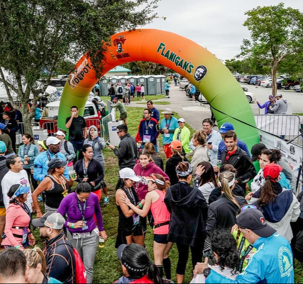 Colorful custom inflatable arch with sponsor logos at running event finish line surrounded by participants