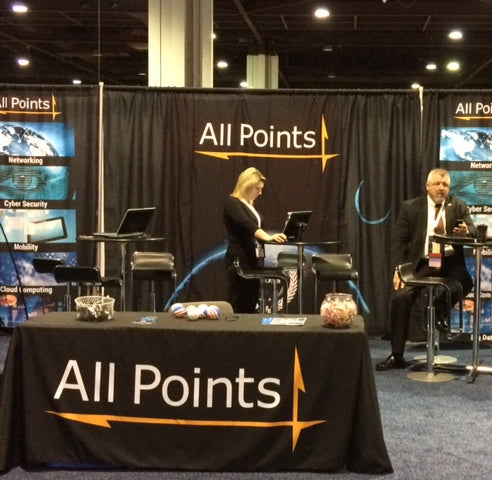 Custom black table cover with All Points logo at trade show booth focused on networking and cybersecurity services