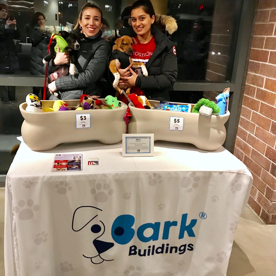 Custom table cover for Bark Buildings indoor pet event with dog toy display and volunteers holding puppies