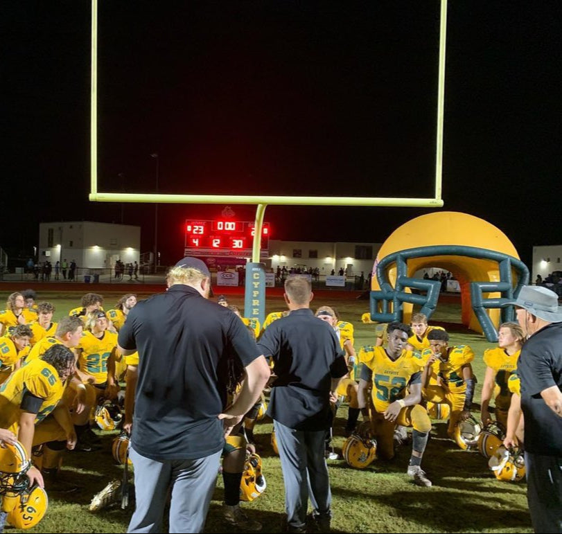 ypress Creek High School football team gathered post-game with inflatable helmet in background