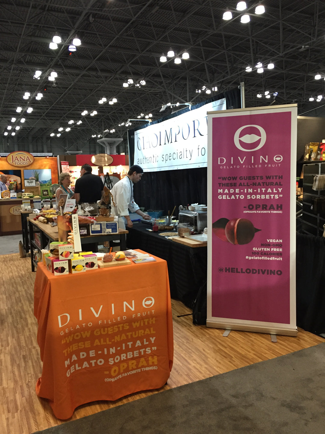 Roll up banner display for Divino Gelato Filled Fruit at trade show booth with promotional branding and sample table.
