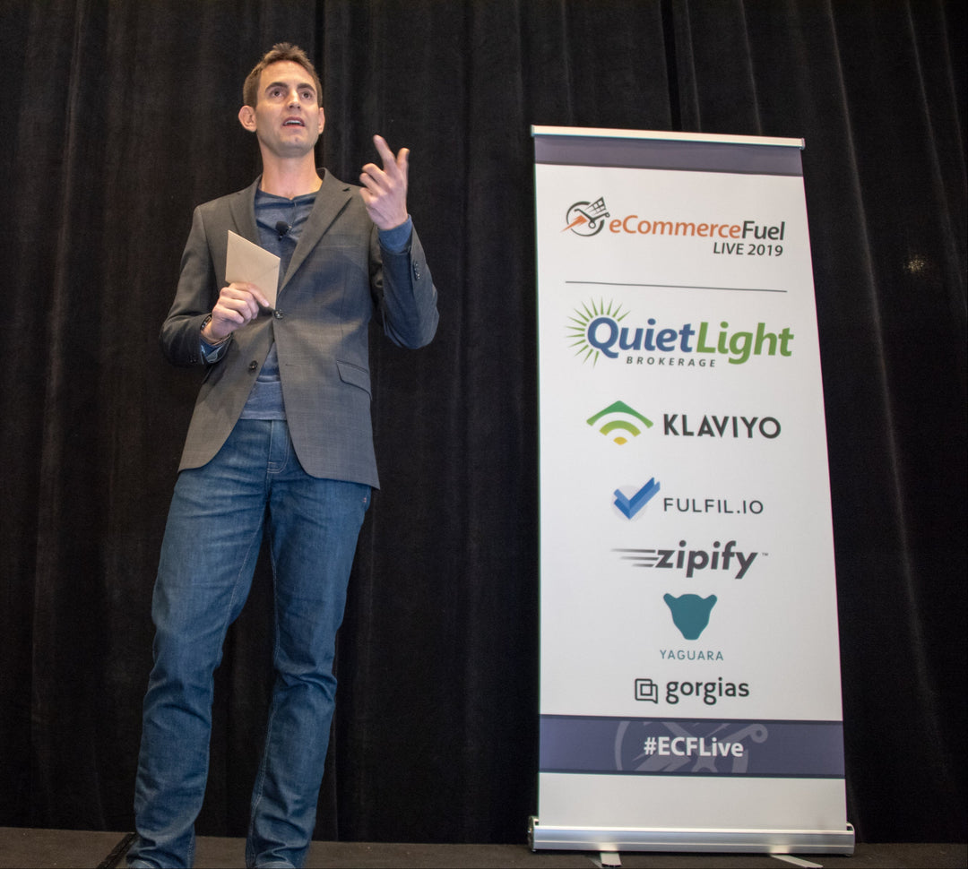 Speaker presenting next to eCommerceFuel Live 2019 event roll up banner