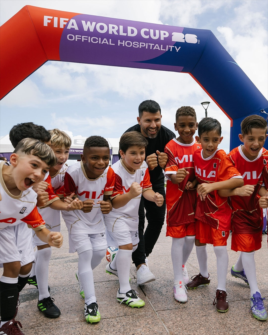 Excited youth soccer players and coach under FIFA World Cup Official Hospitality inflatable arch
